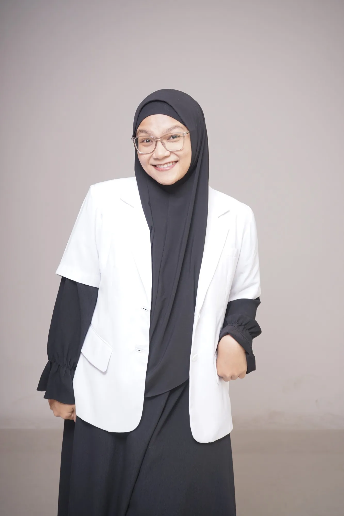 Potret drg. Shafira Noor Latifah mengenakan jas dokter putih dan kerudung hitam, tersenyum